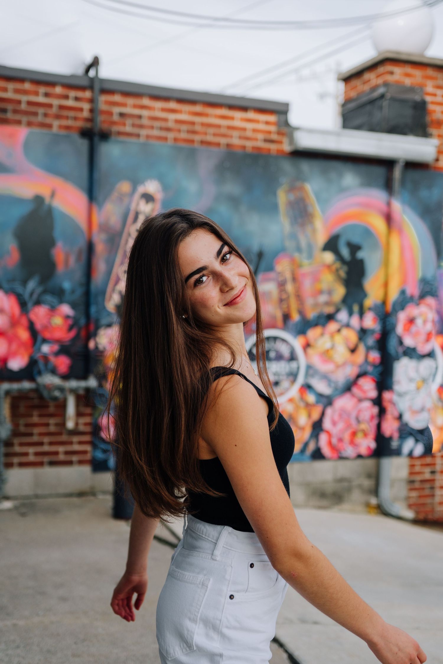 Portrait against colorful graffiti wall with flowers and rainbow designs.