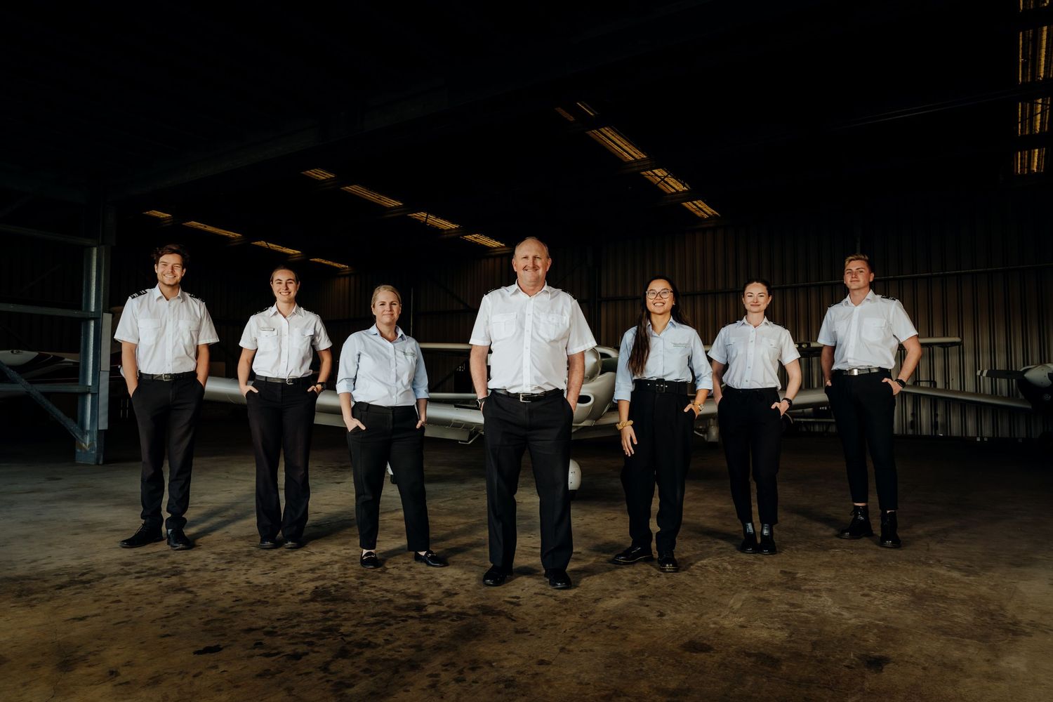 Flight instructors in front of an aircraft in a hangar