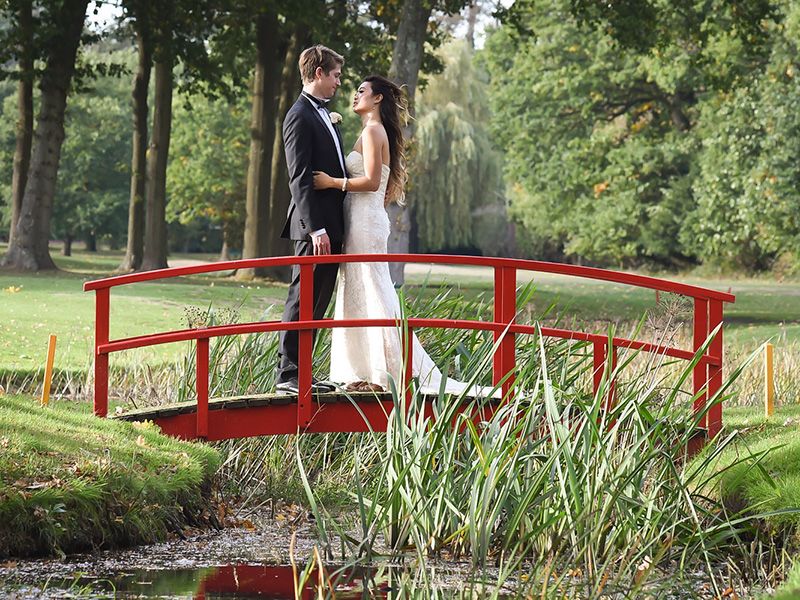 Bride and Groom stand on traditional Japanese red bridge in stoke place. Wedding photographer Abigail's Studio