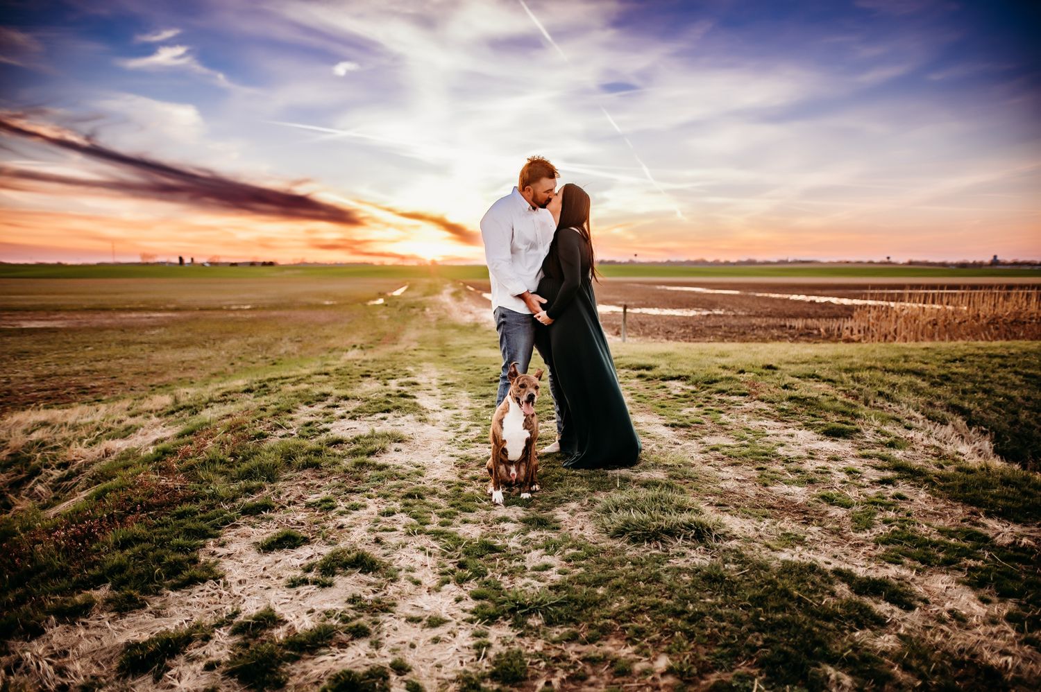 Dreamy sunset engagement session in an open field with dramatic clouds.