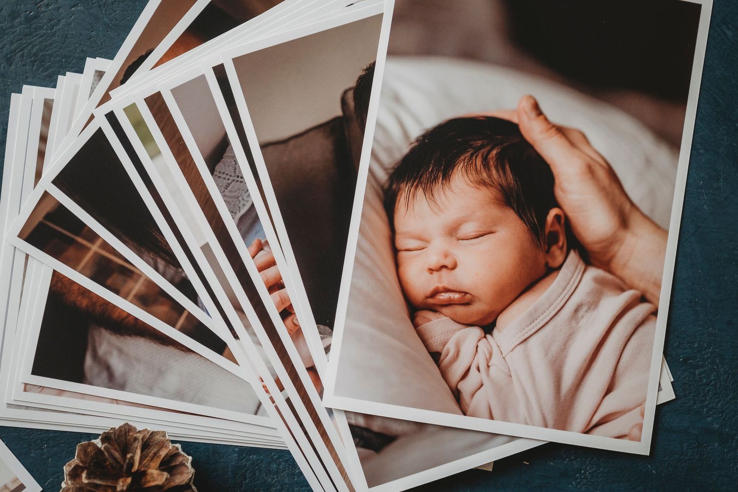 Collection of printed photographs spread out with a sleeping newborn featured.
