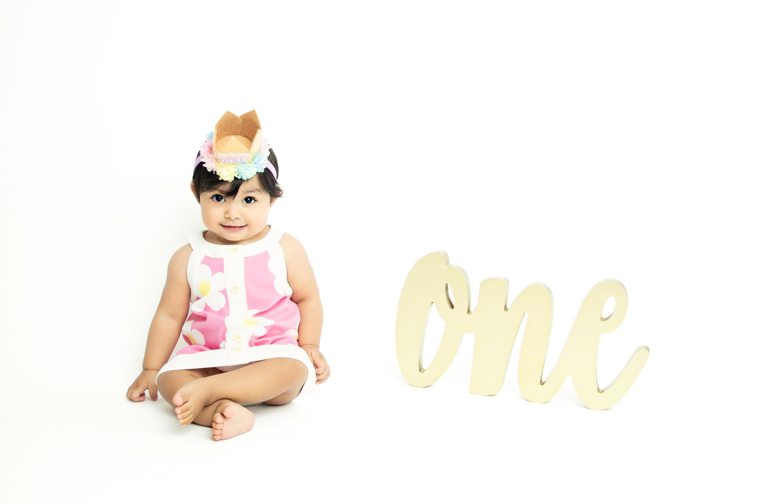 Simple white studio setup with gold 'one' text and pink floral accents.