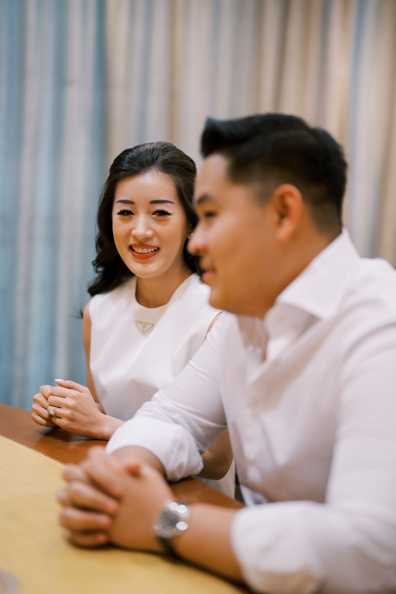 Two people in white outfits having an animated conversation at a wooden table.