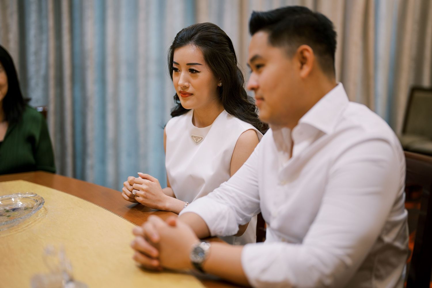 Two people in white attire sharing a lighthearted moment at a meeting table.