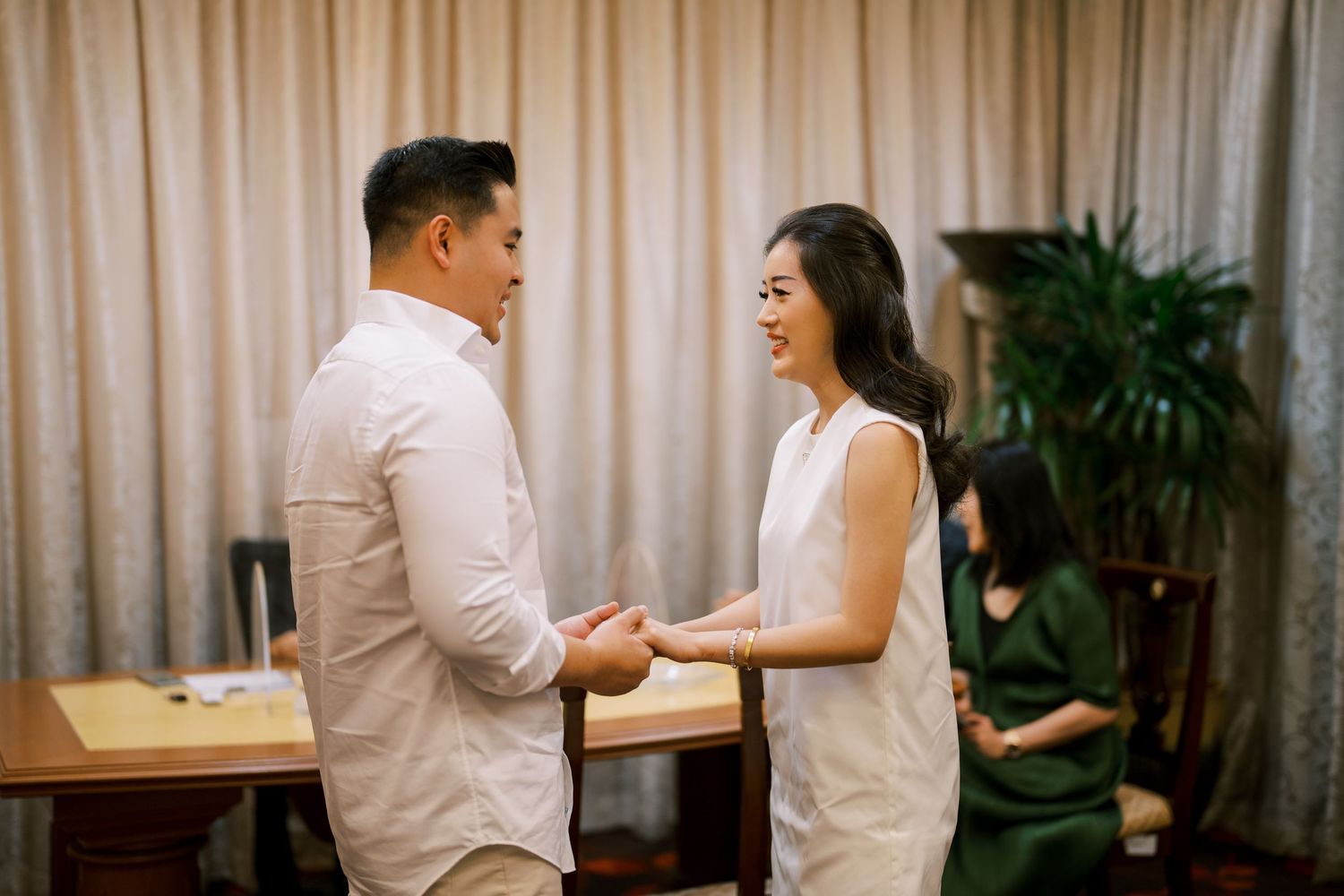 Two people in white outfits interacting playfully in a meeting room setting.