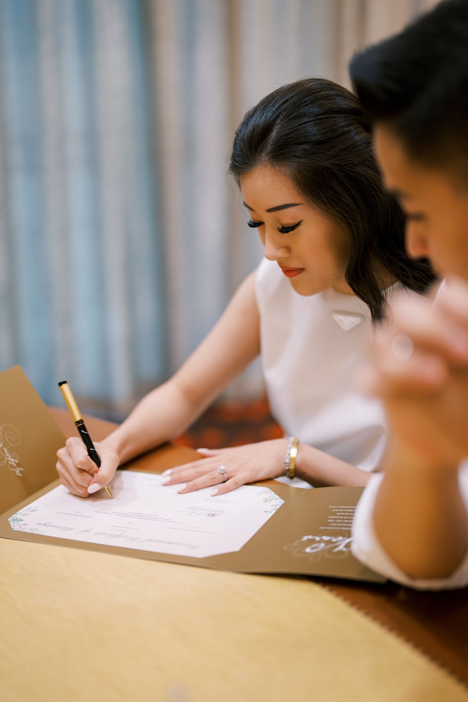 Multiple people in white shirts signing documents at a table during a formal gathering.