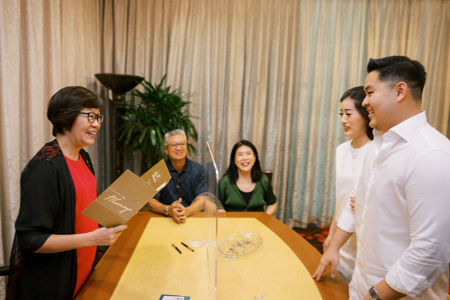 Group of people gathered around a large wooden conference table for a meeting.