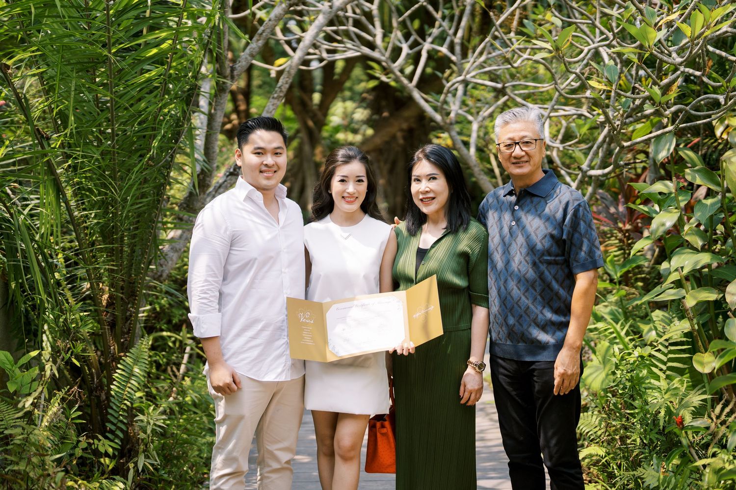 Group photo taken outdoors with lush green foliage in the background.