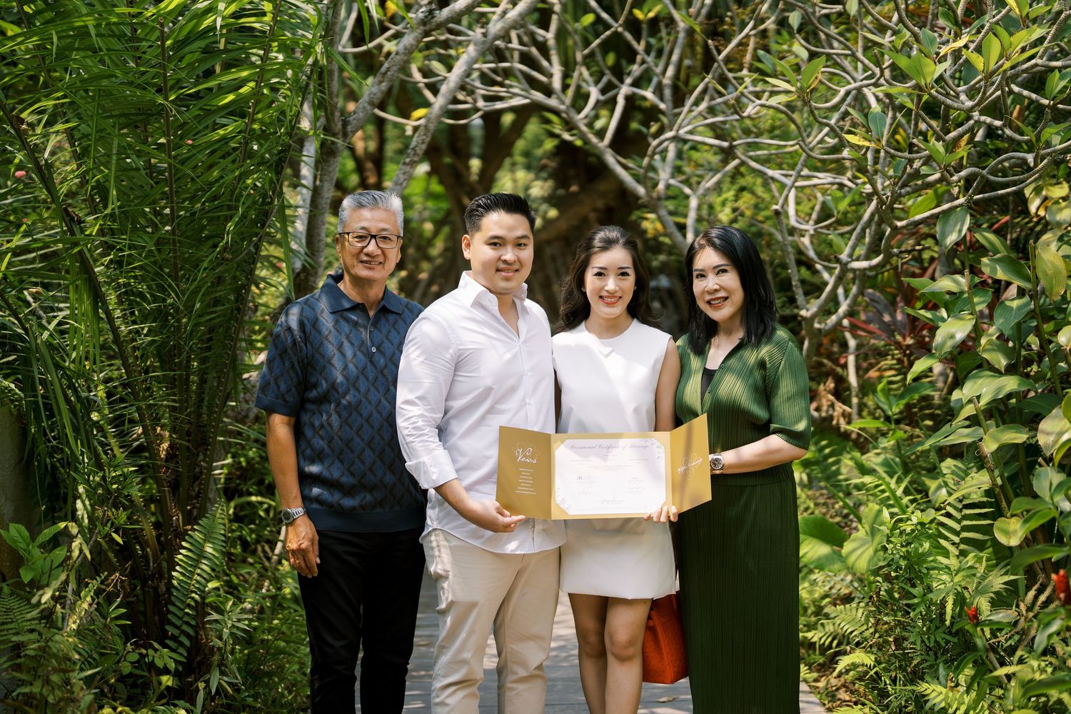 People posing for a group photo in a garden setting with tropical plants.