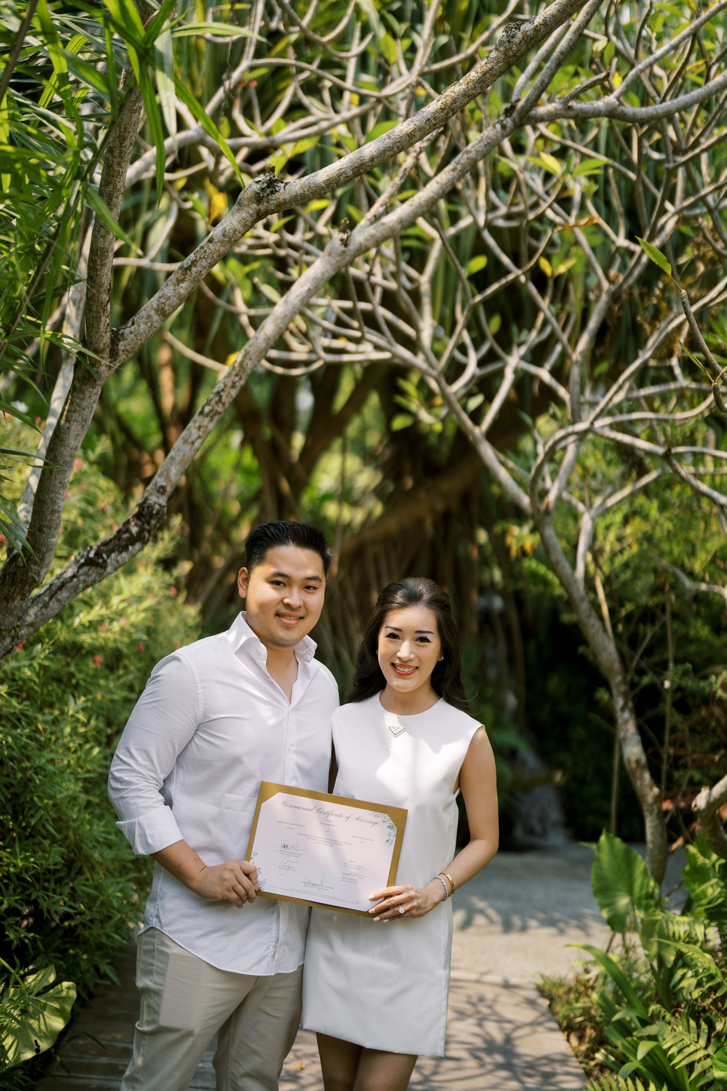A couple in white outfits sharing a special moment together in a lush garden setting.