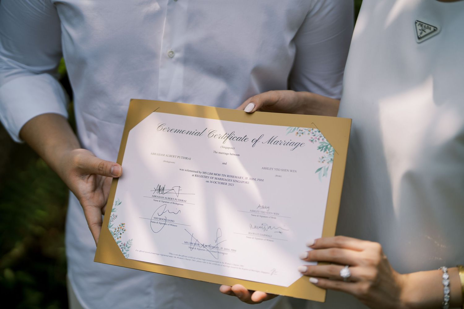 Close-up view of hands holding an official certificate document outdoors.