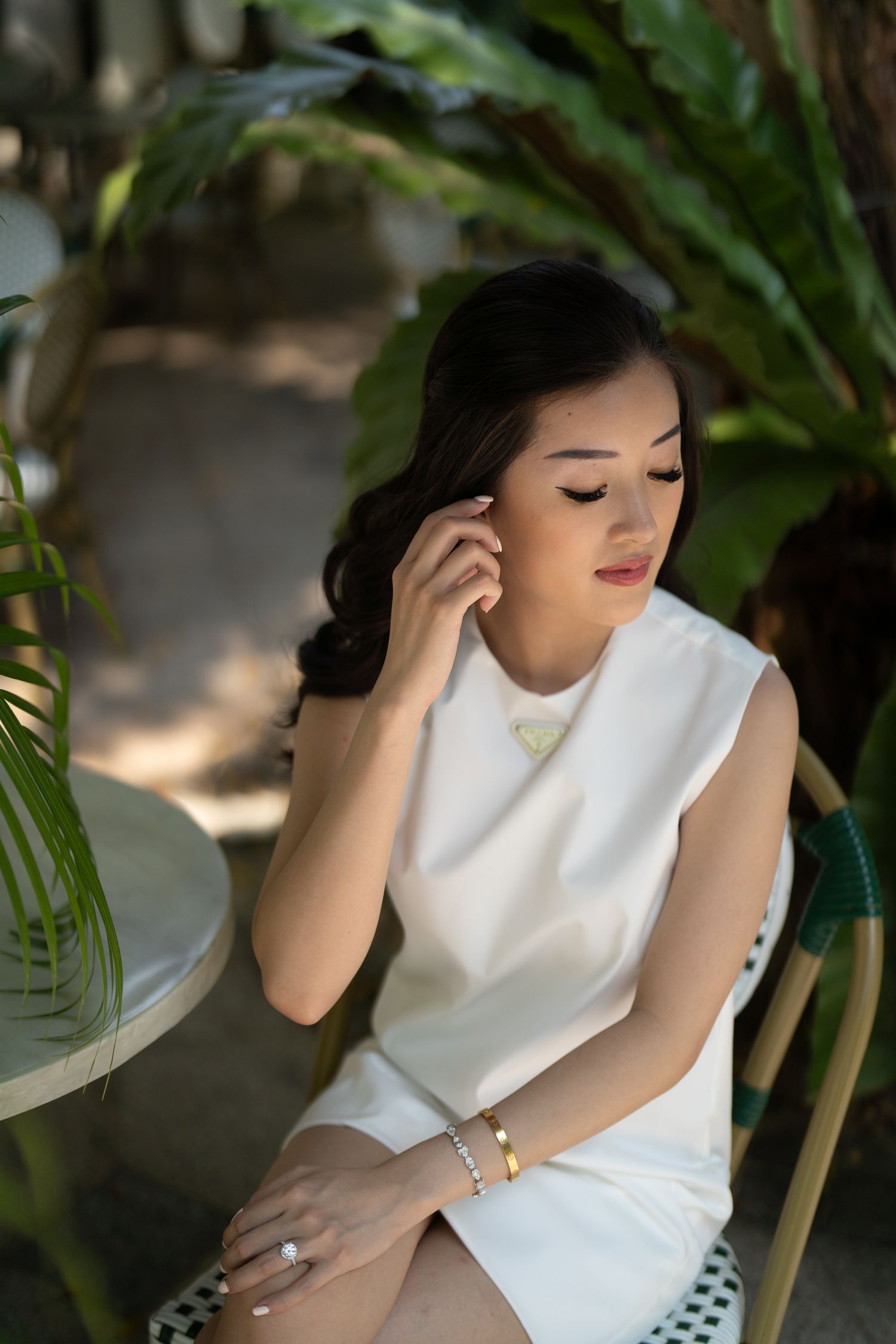 Artistic portrait of someone in white against lush tropical foliage background.