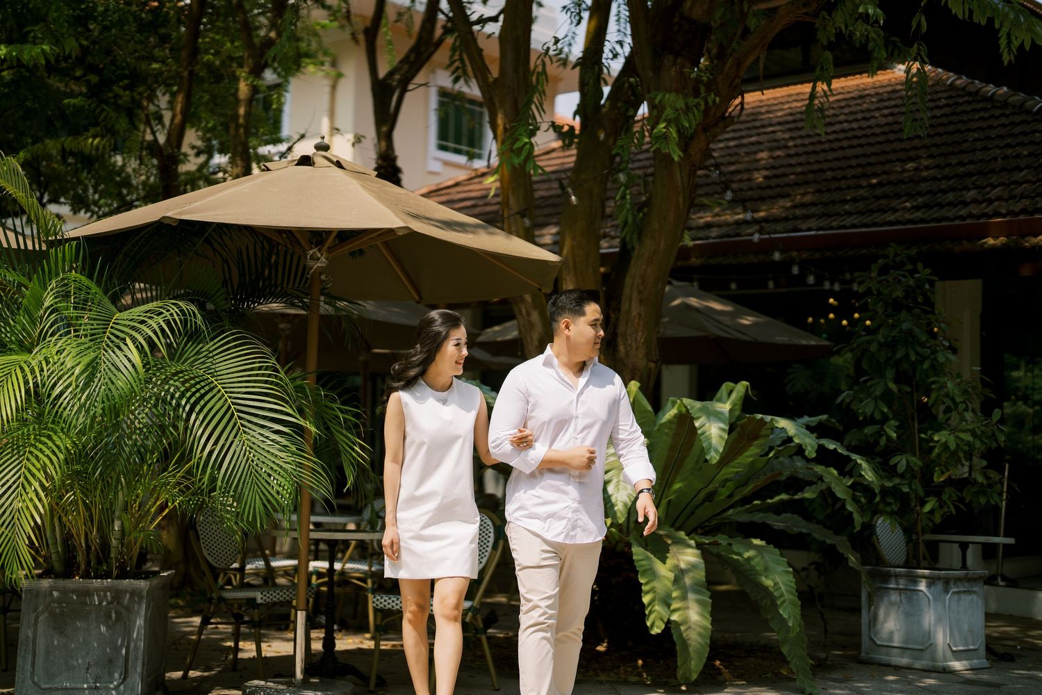 Romantic scene in a garden with beige umbrellas and tropical plants creating a serene atmosphere.