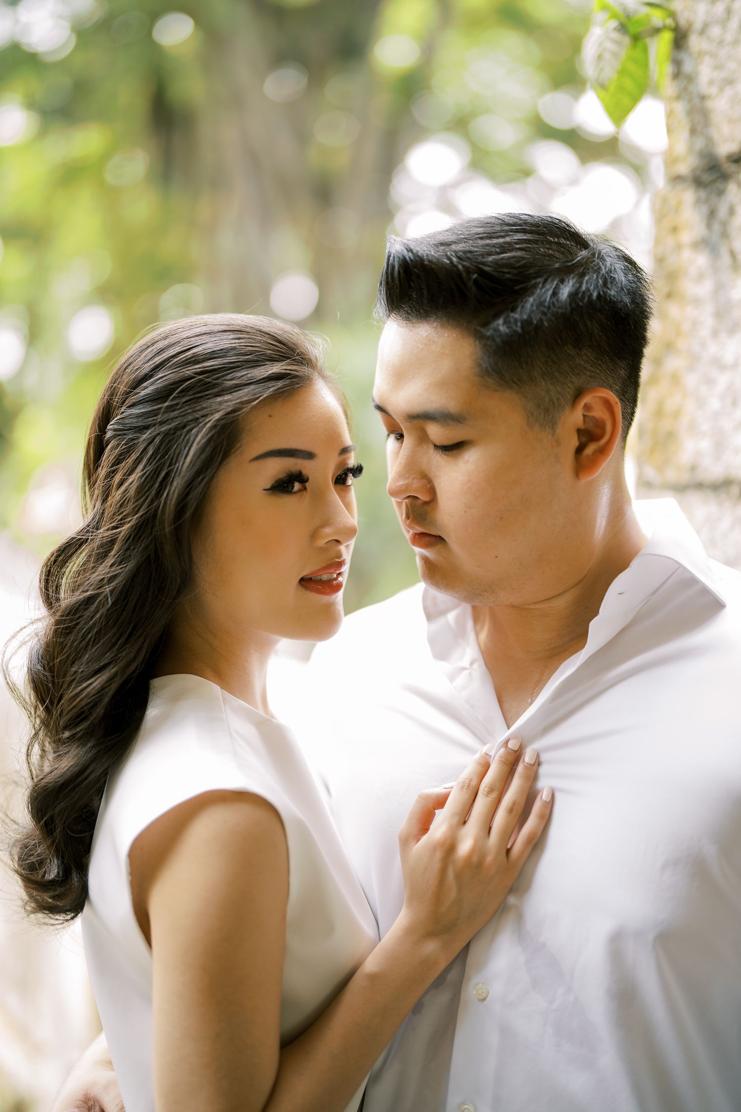 Tender moment photographed in natural lighting with bokeh effect and greenery.
