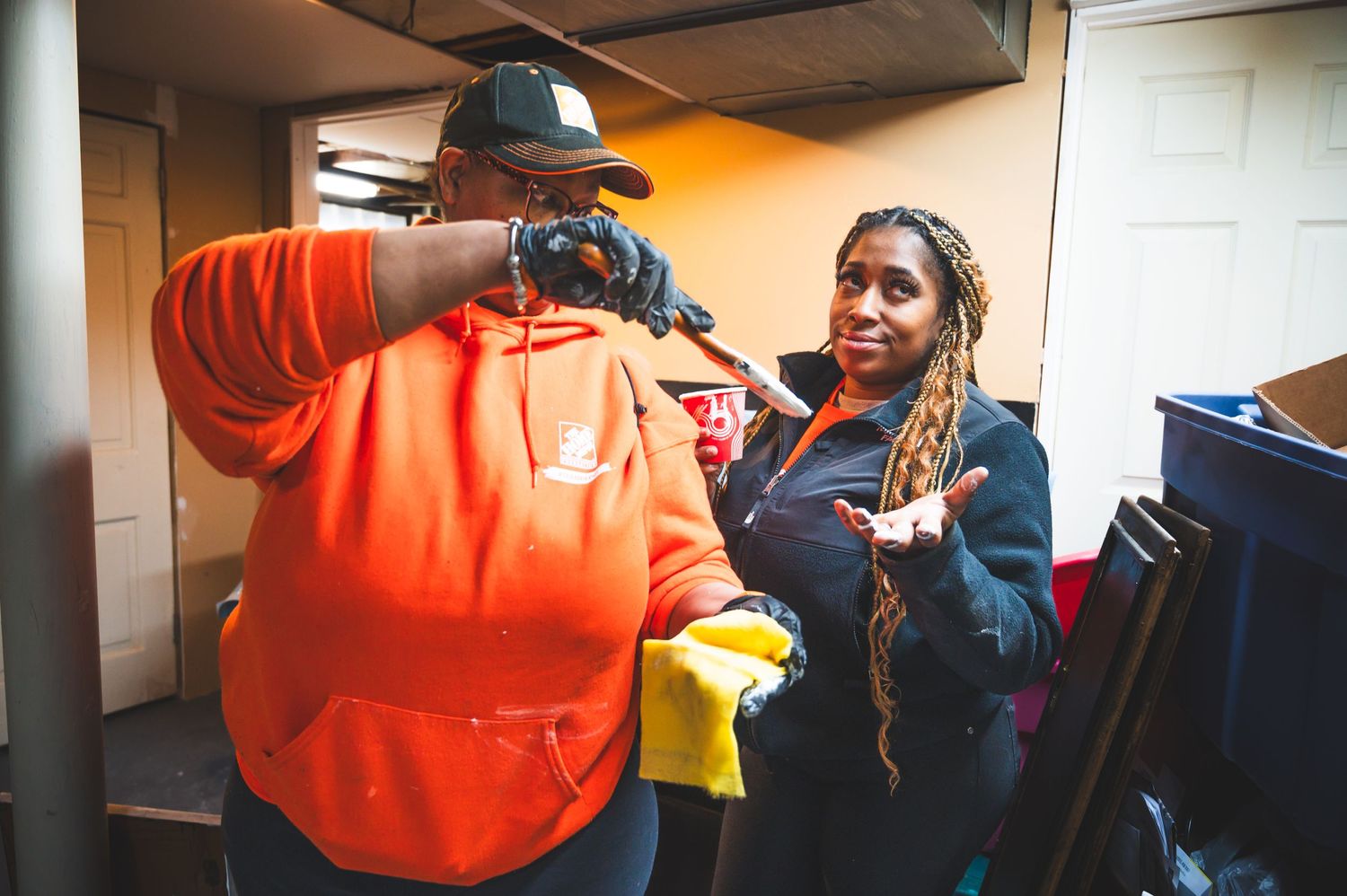 Two volunteers in orange shirts have a friendly interaction while working on a community service project.