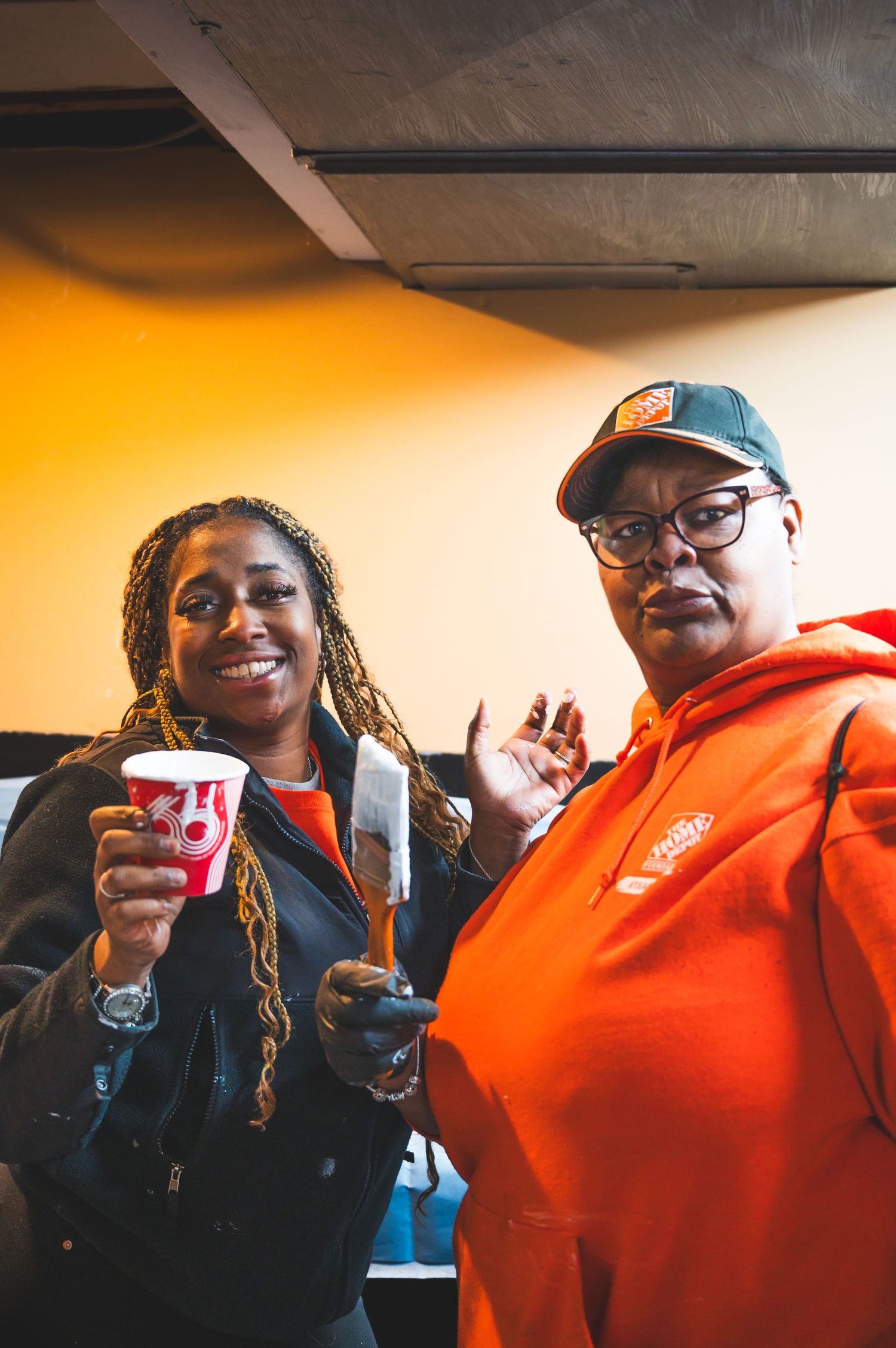 Two people in casual attire enjoying refreshments during indoor gathering.