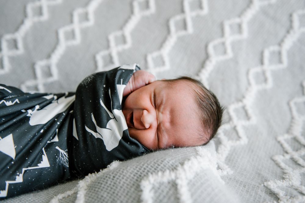 Peaceful newborn sleeping on white textured blanket.