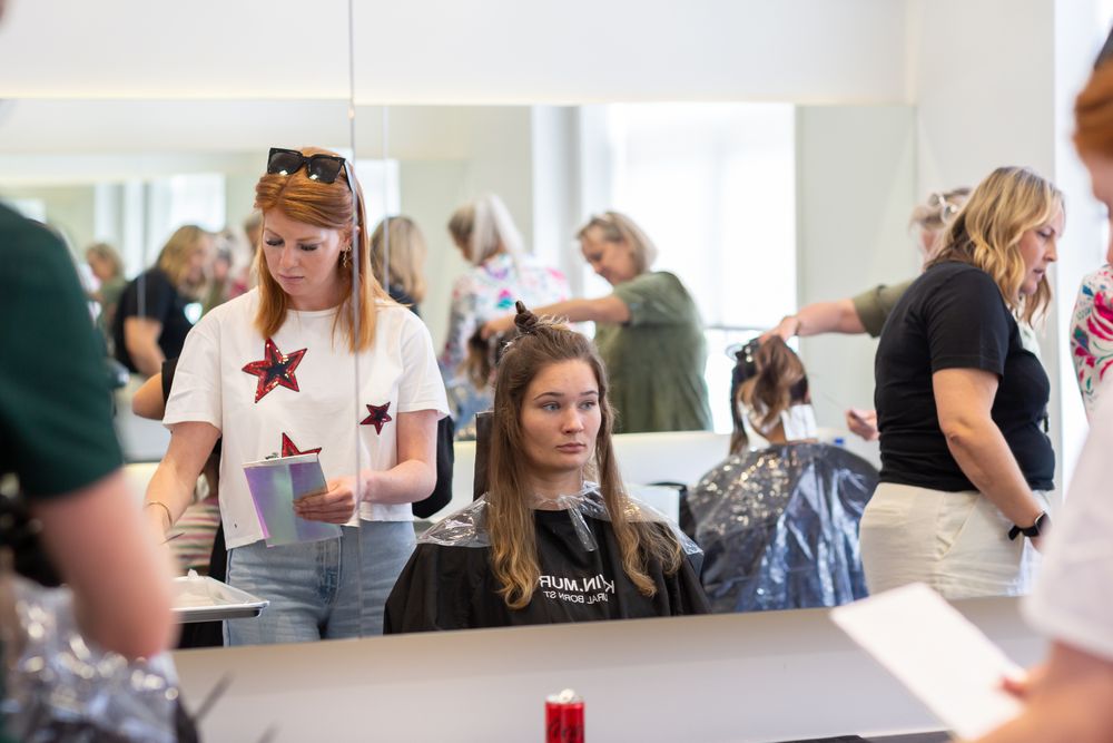 Busy hair salon scene with stylists working on clients' hair treatments.