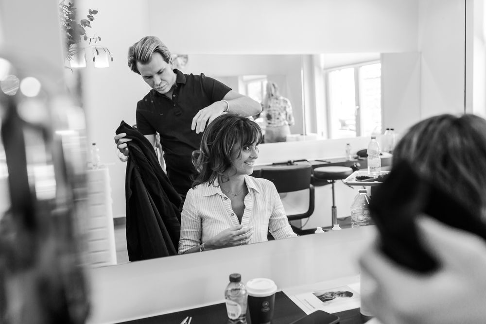 Black and white photograph of salon professionals working with clients in modern setting.