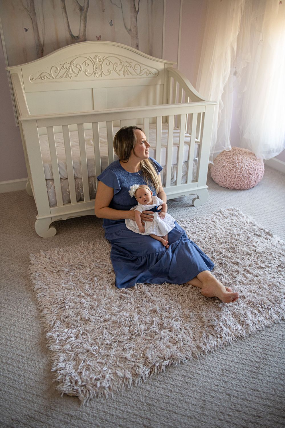Family photo session in a nursery with white crib and plush carpet showing tender moments.
