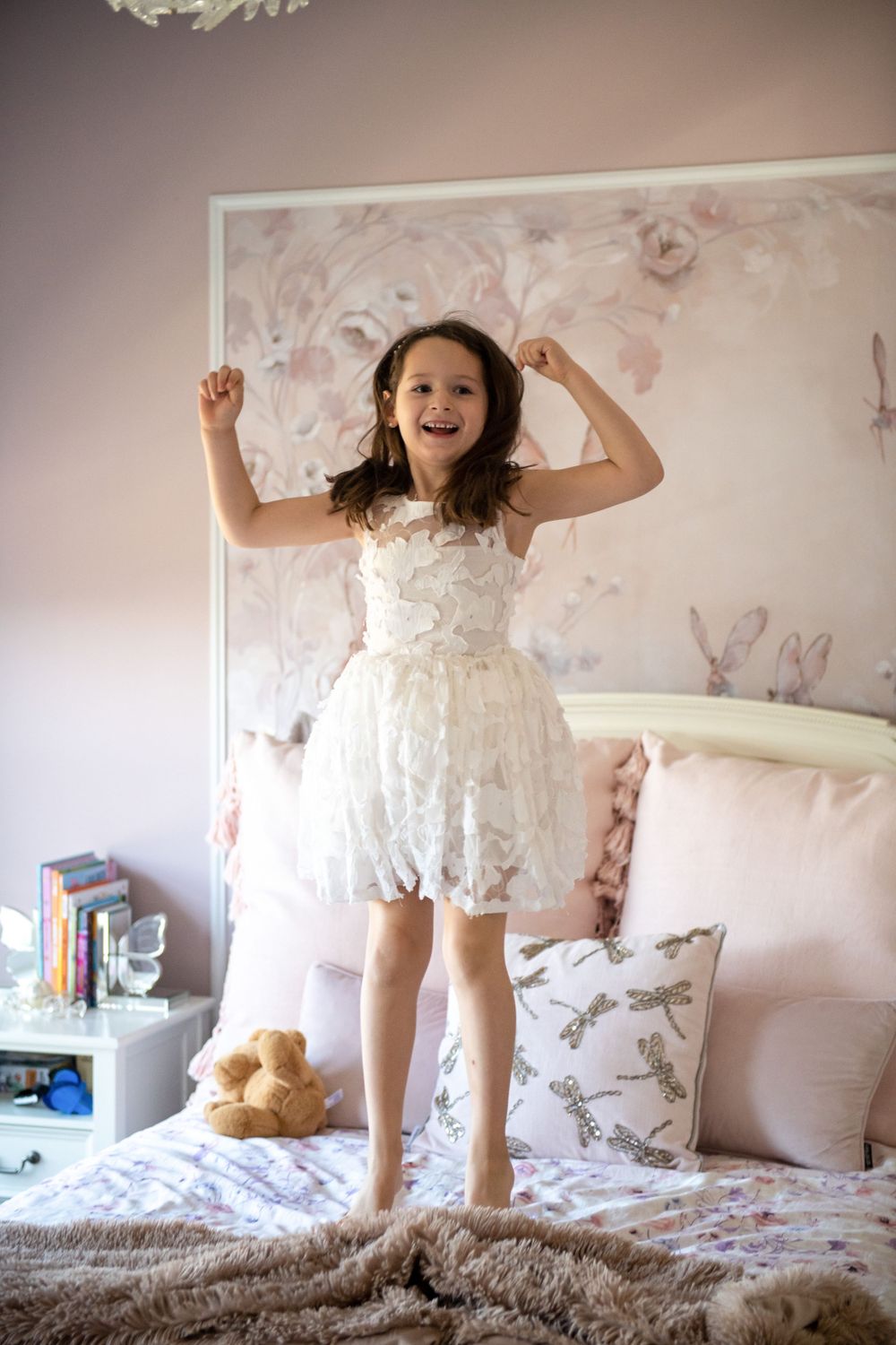 Playful moments on a bed with floral wallpaper in the background.