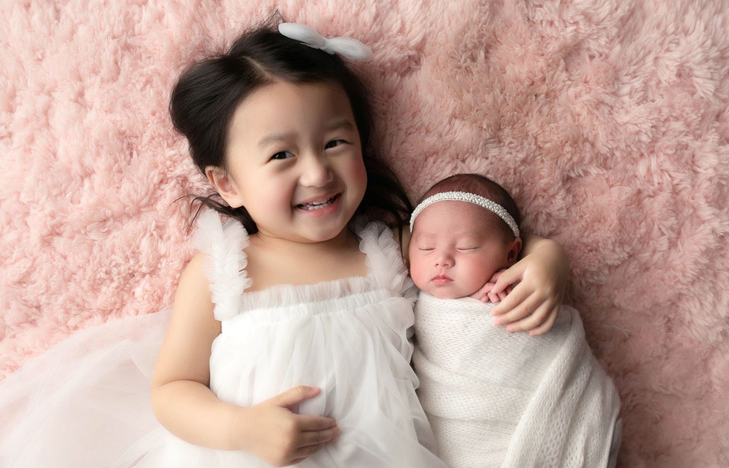 An Asian big sister holding her newborn sister. Greenville, SC newborn photographer; Easle SC newborn photographer, Upstate newborn photogra