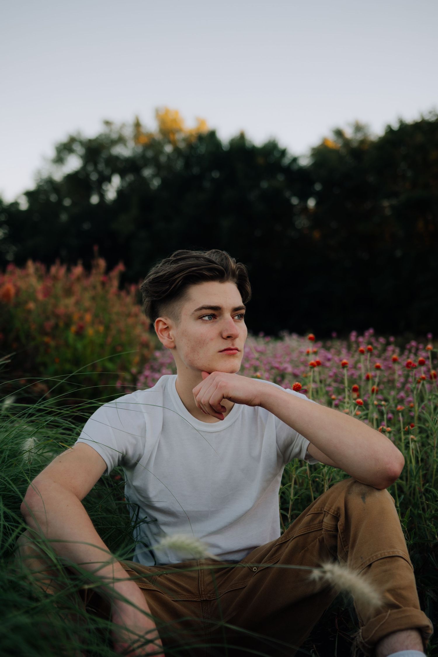 A thoughtful portrait of someone sitting in a wildflower field at golden hour.