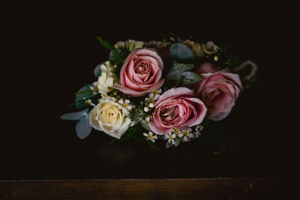 Close-up of wedding rings resting on a bed of roses