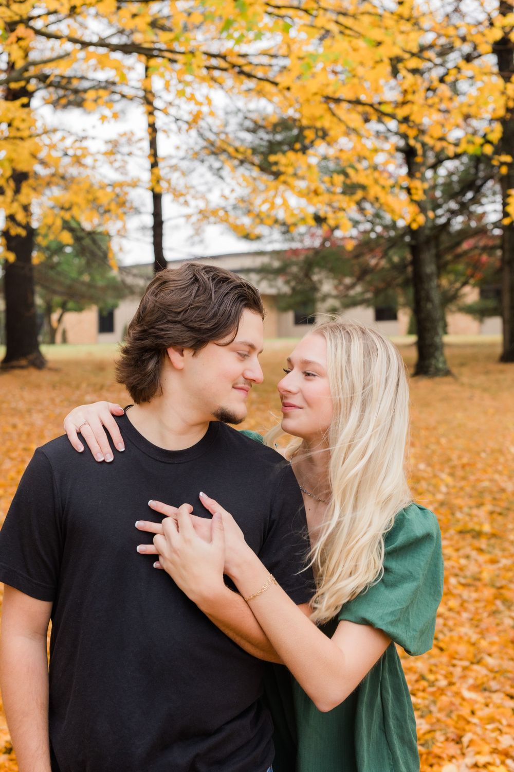 Romantic couple embracing under yellow fall foliage in a park setting.