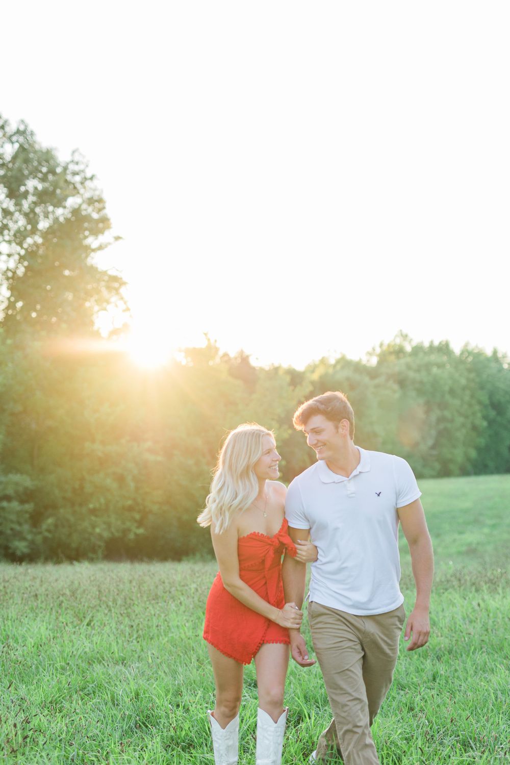 Couple walking together in a sunlit meadow during golden hour.
