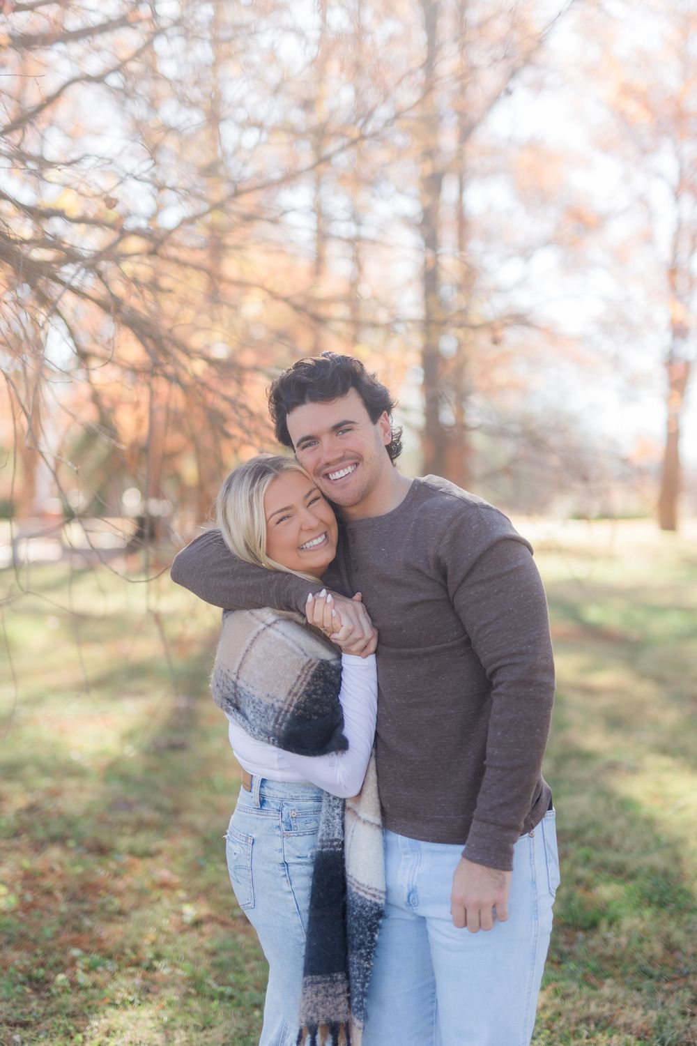 A couple embraces and laughs together in a fall outdoor setting.