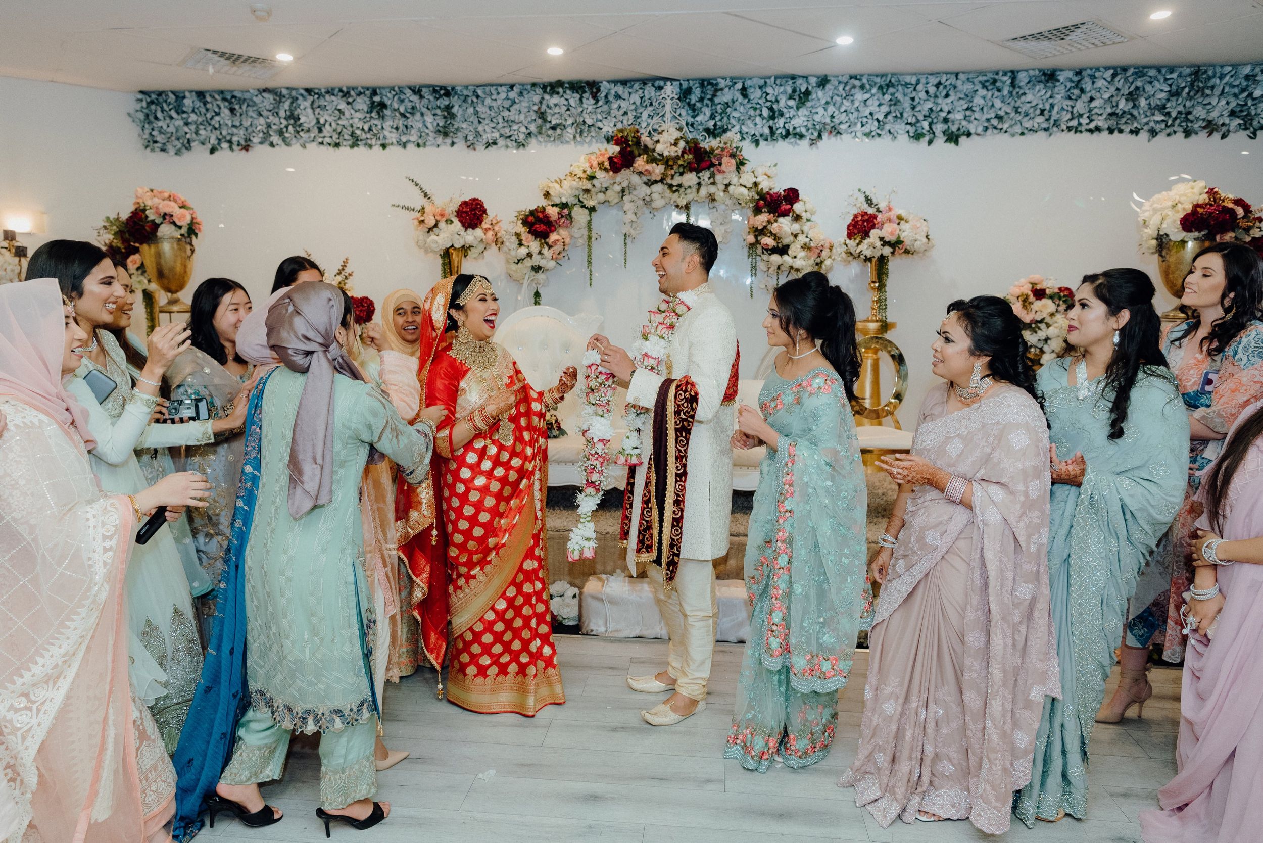 Wedding party celebration with guests in pastel and vibrant traditional outfits.