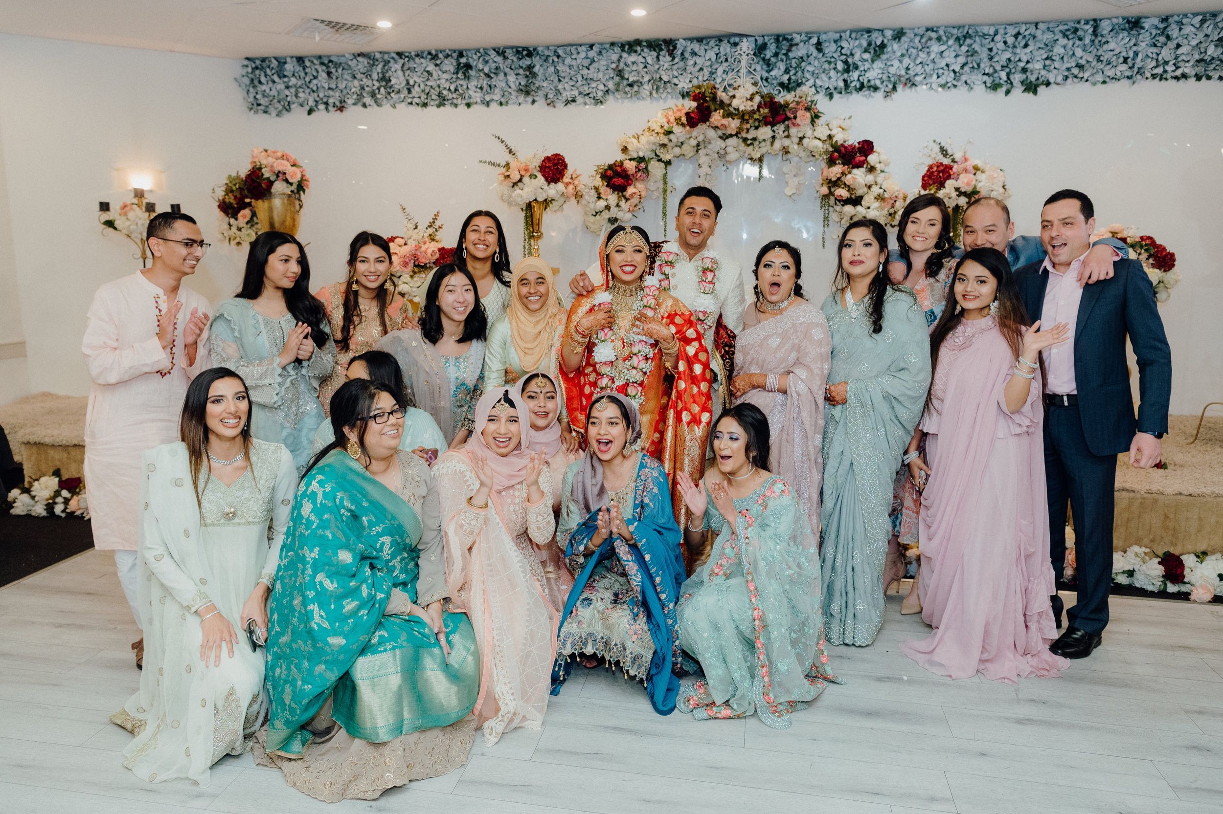 Group celebration photo with wedding party in mix of traditional and modern attire.