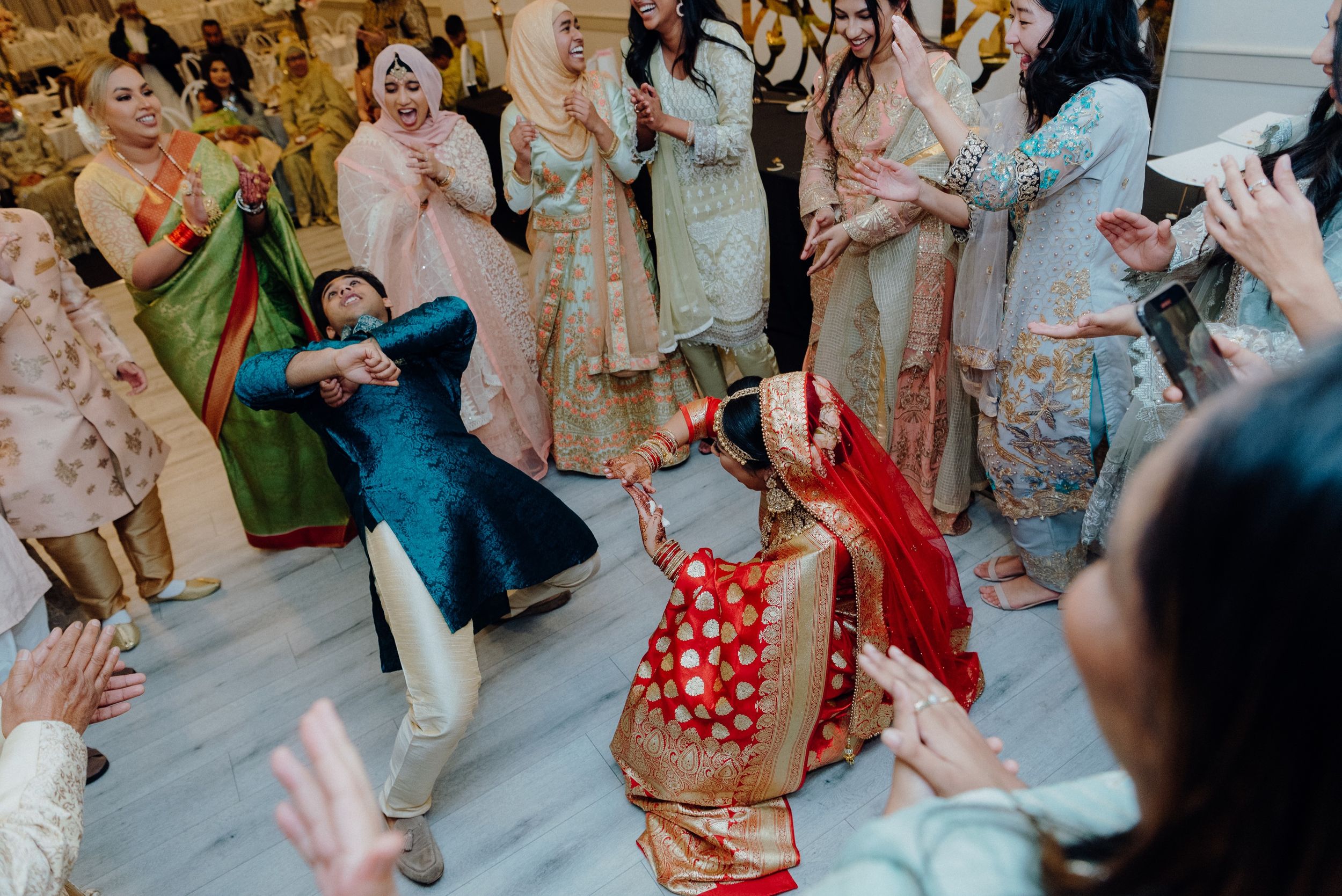 Energetic dancing and celebrations at a multicultural wedding reception with colorful traditional outfits.