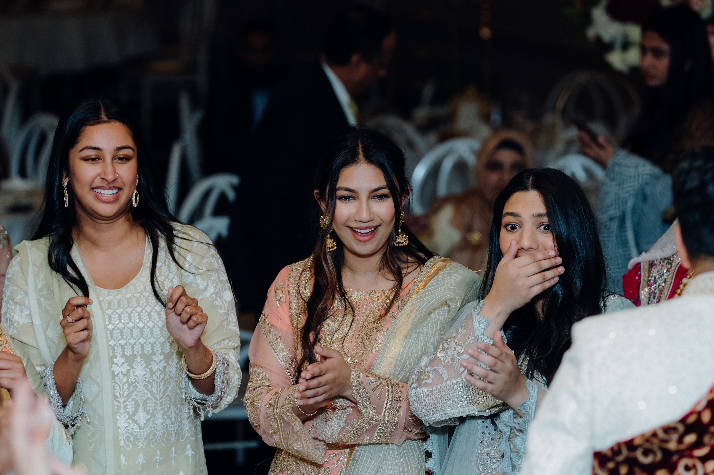 Guests in elegant traditional attire sharing a fun moment at a wedding celebration.