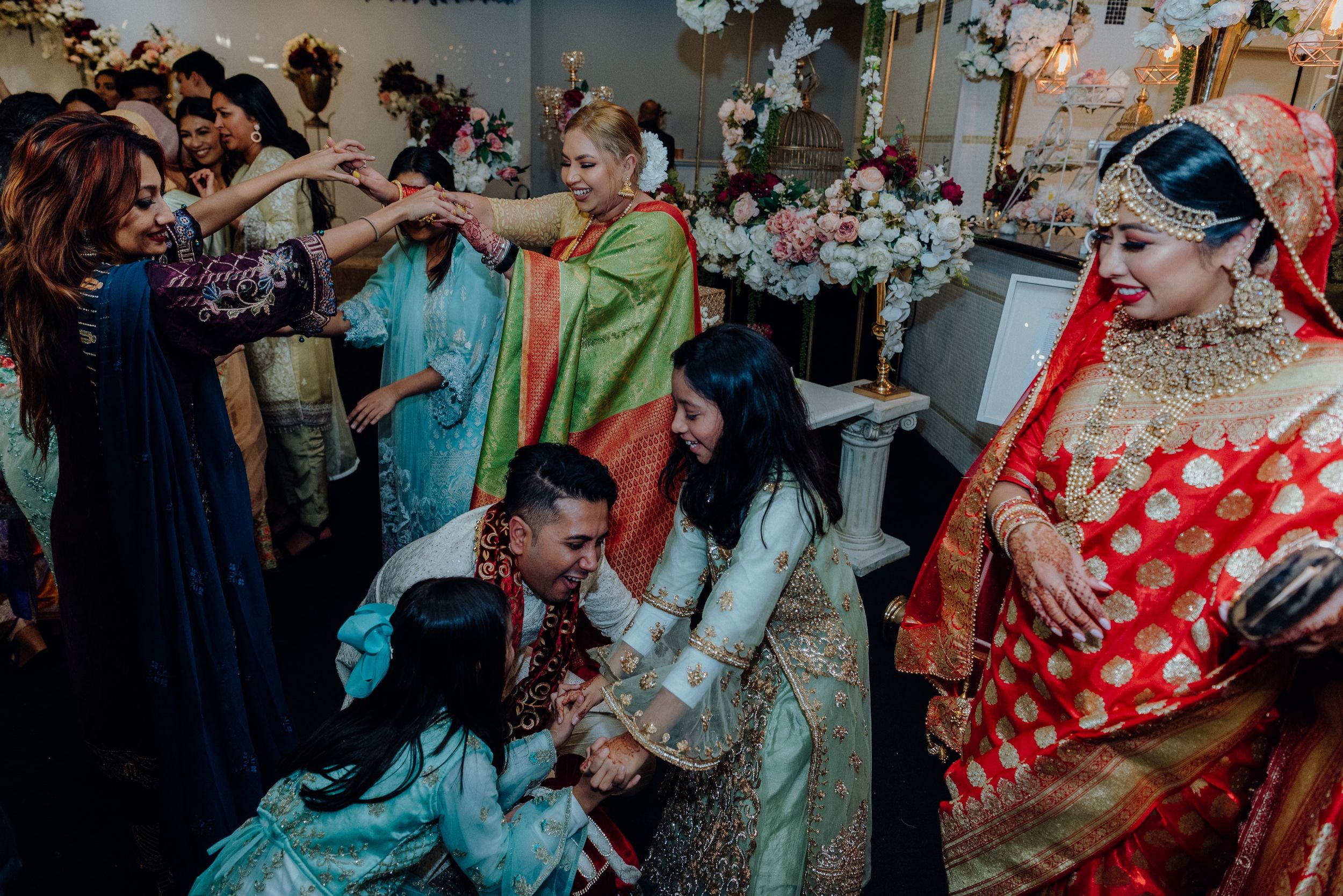 Lively dance floor scene from a multicultural wedding with guests in vibrant traditional attire.