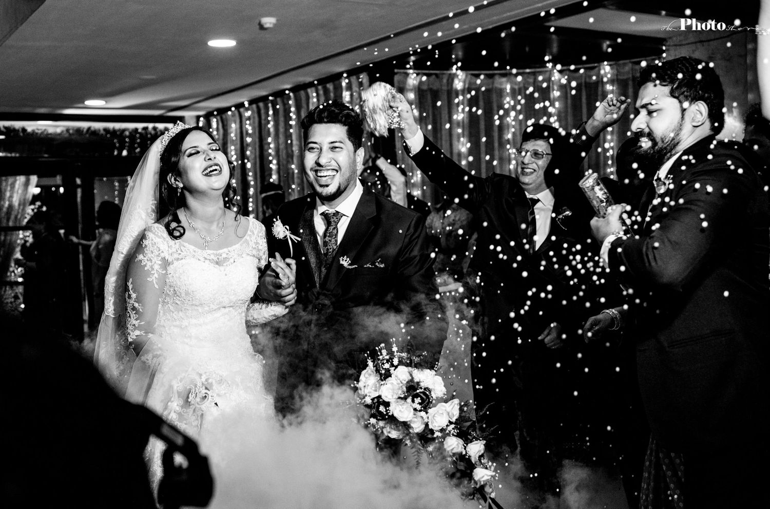 Wedding celebration with string lights and guests dancing in an elegant indoor reception venue.