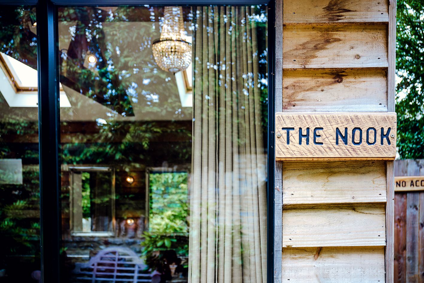 Vintage window display with 'The Nook' sign and crystal chandelier reflections.
