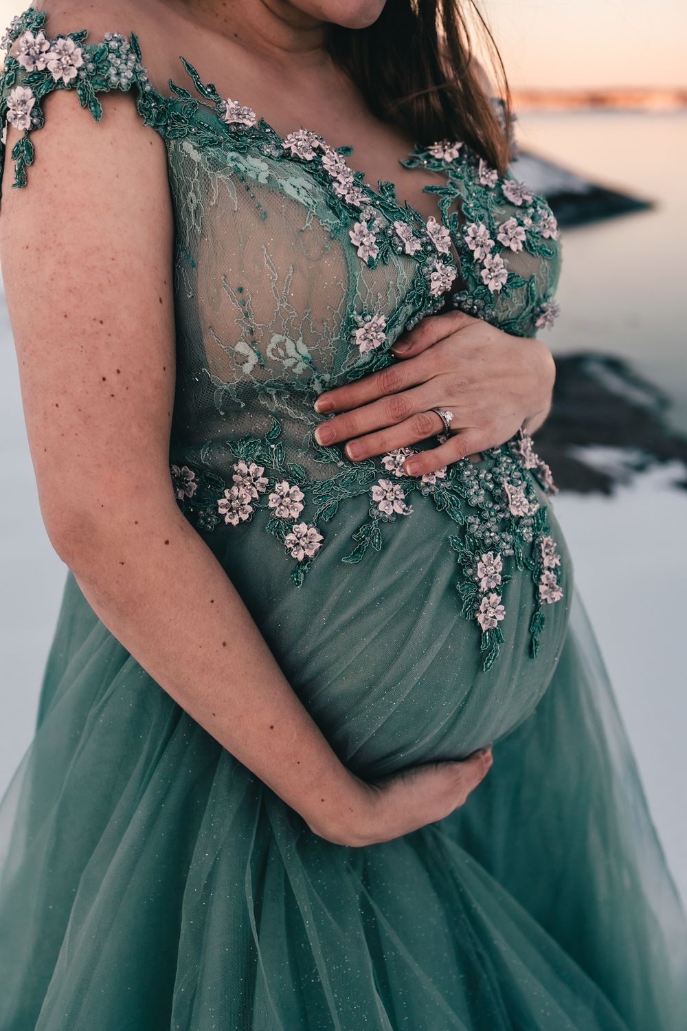 Detail shot of teal maternity gown with delicate floral embellishments.