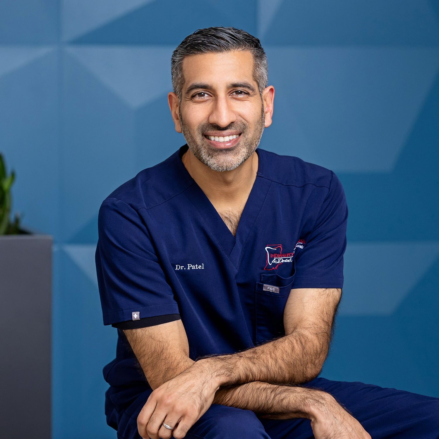 Medical professional portraits in navy blue scrubs against a blue background.