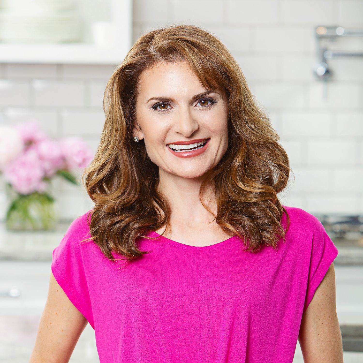 Lifestyle portraits of someone wearing a bright pink top in a modern kitchen setting.