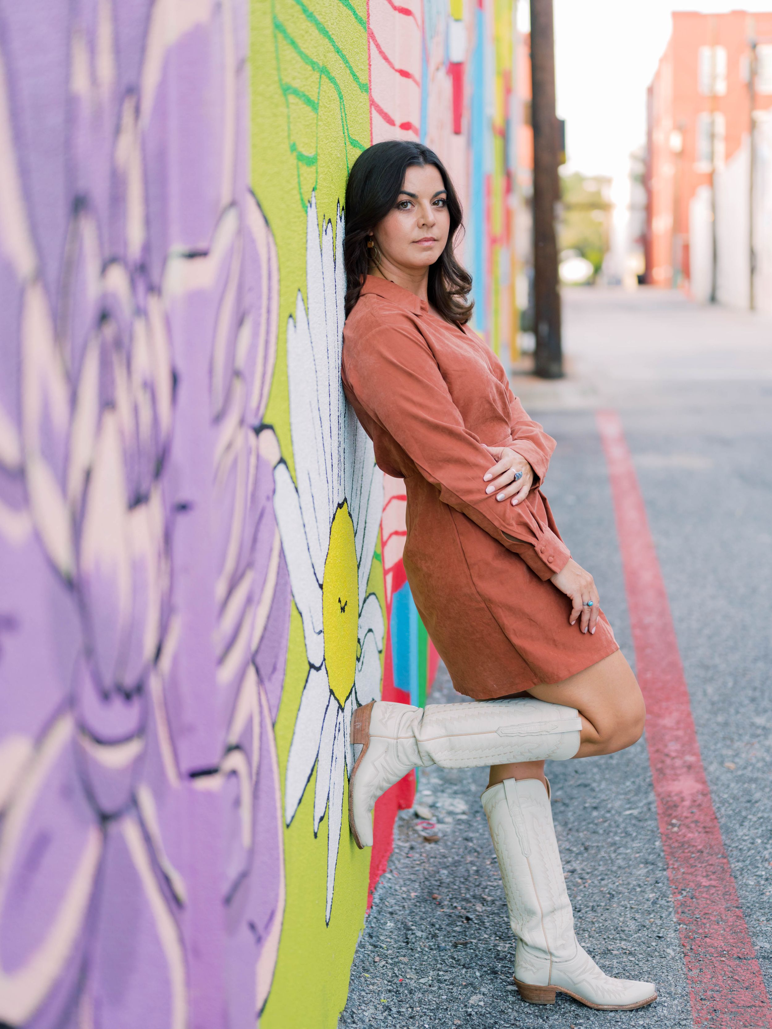 branding photo of a woman leaning against a wall with a mural in Downtown McKinney