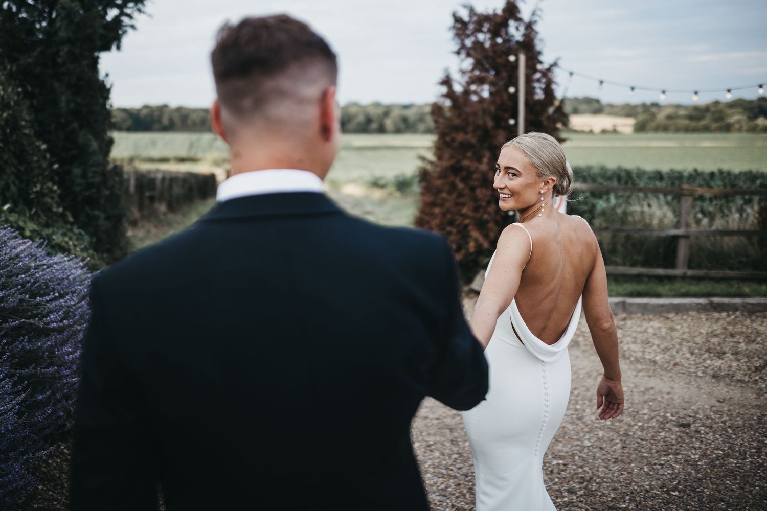 Bride leading her groom down into the cornfields at swancar farm