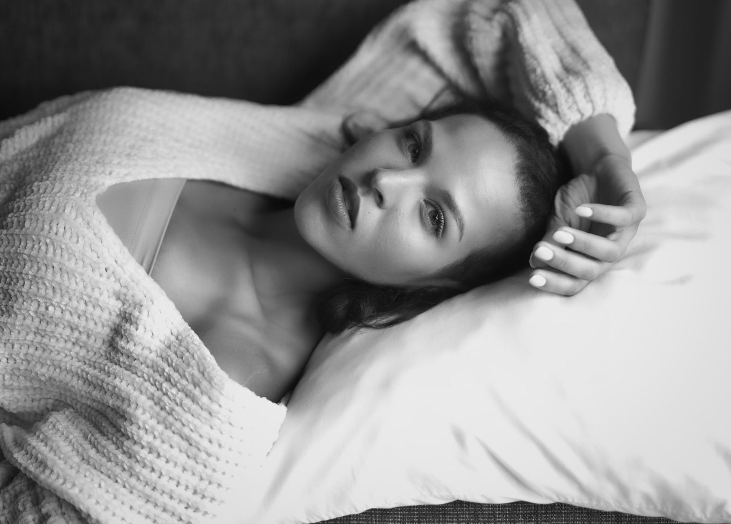 A boudoir photography session featuring intimate poses in a dimly lit bedroom setting.