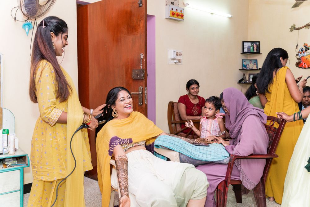 A group in yellow and purple traditional attire gather in a room during what appears to be a pre-wedding celebration.
