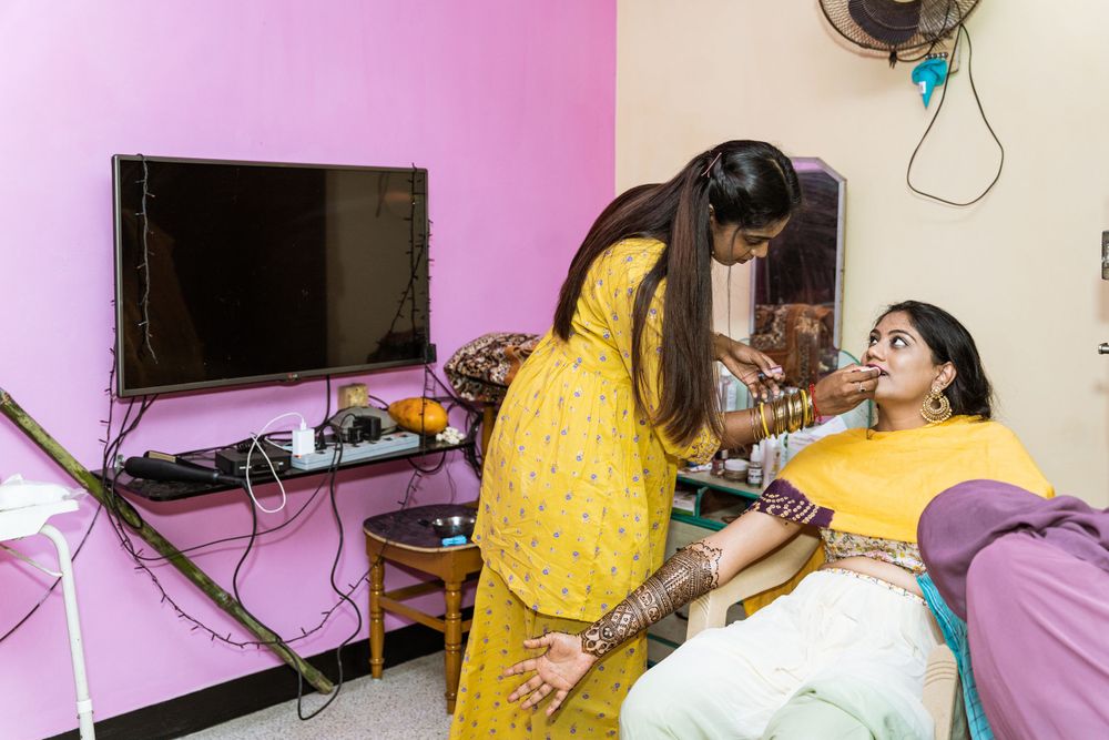 Women in colorful attire applying henna designs in a home setting.