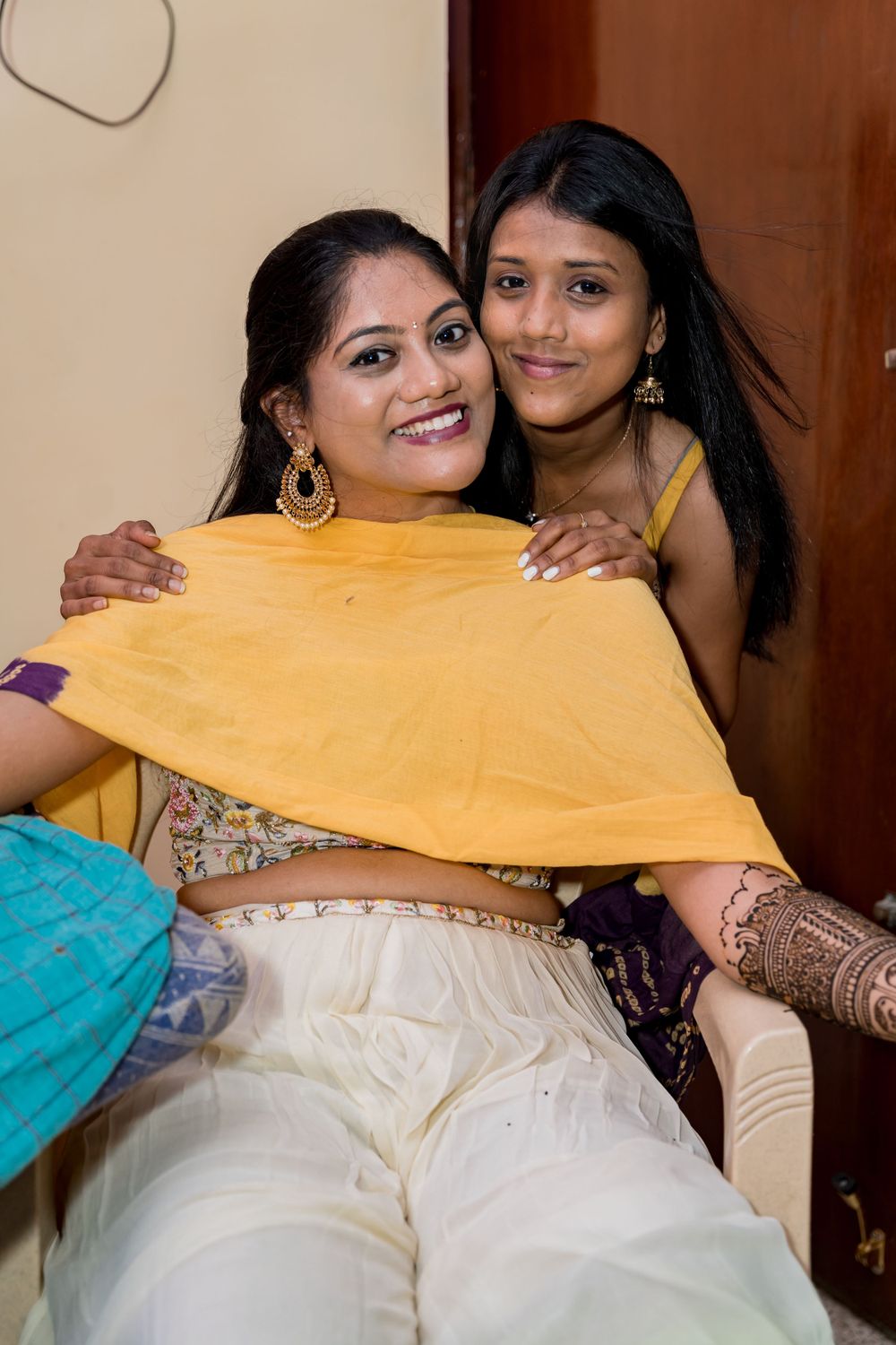 Two people share a joyful moment while wearing traditional Indian attire with intricate henna designs.