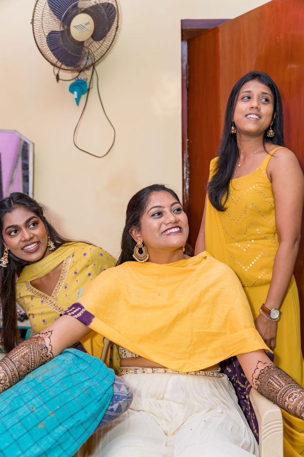 A festive gathering shows people in bright yellow and traditional Indian clothing posing together.