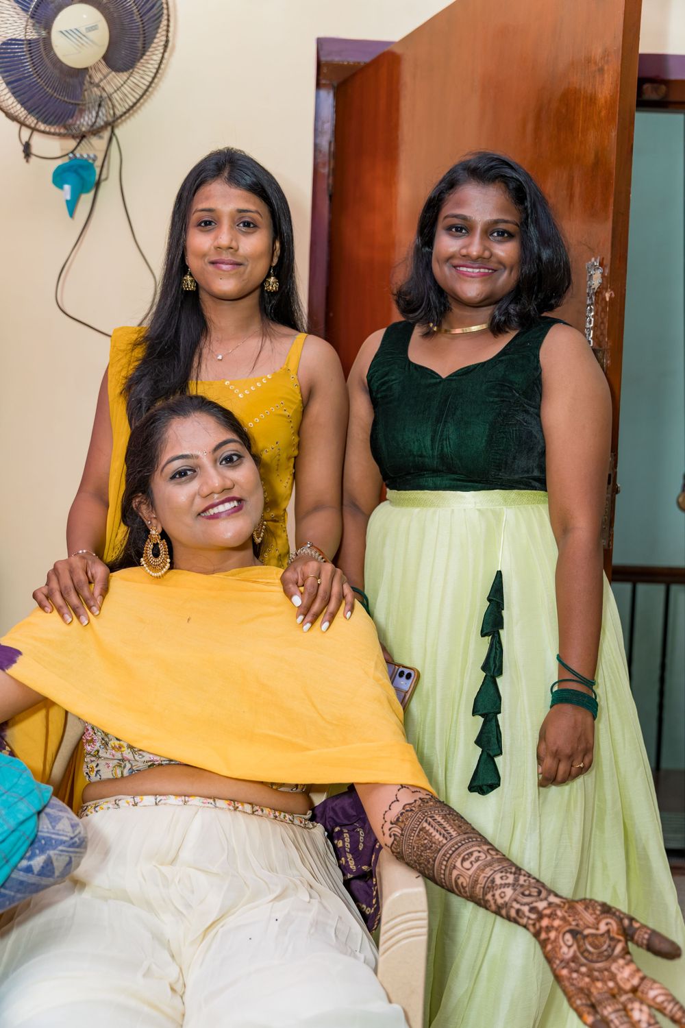 Three people pose together during a celebration wearing coordinated festive attire in yellow and green.