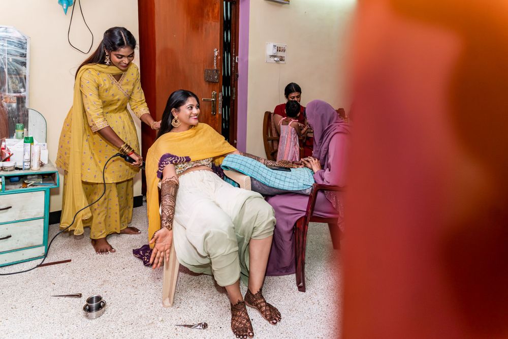 Women in yellow and purple attire gather around someone seated during a celebration.